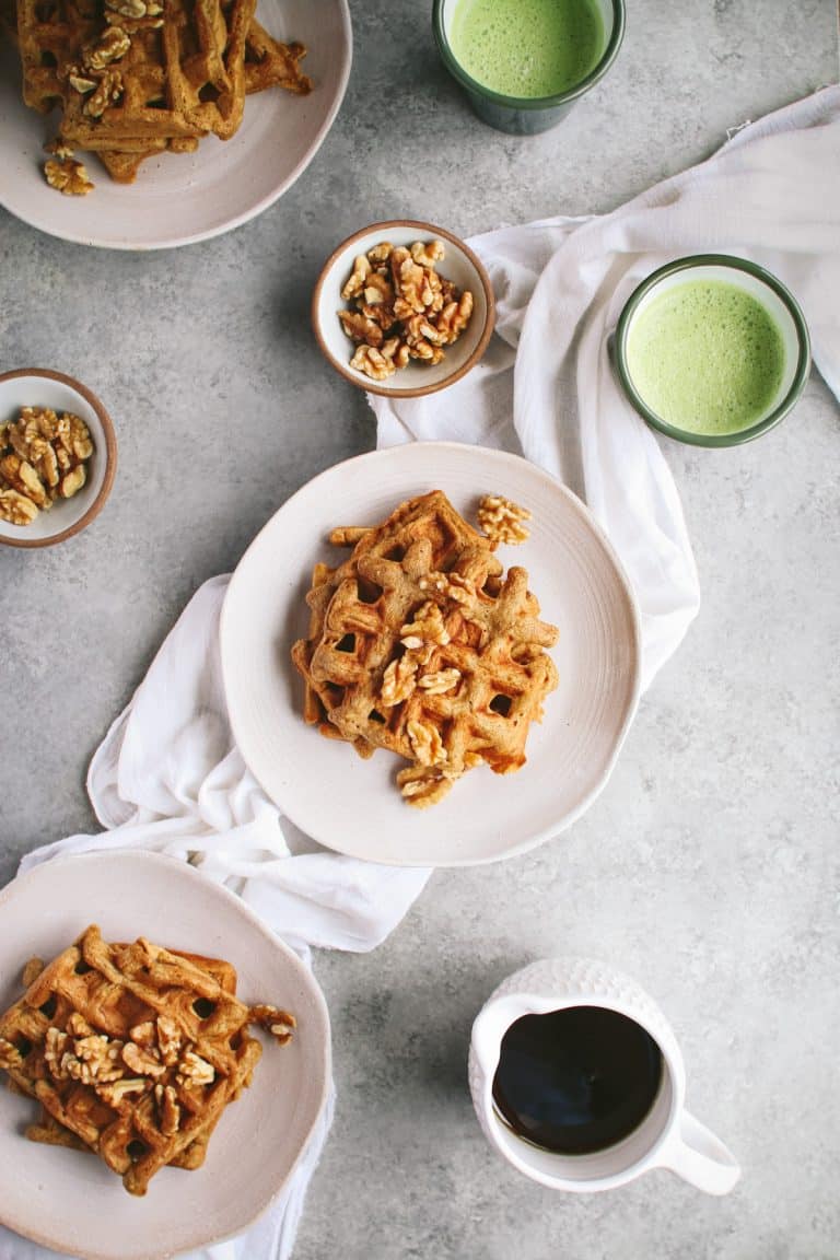 Three plates of vegan applesauce waffles on a gray background.