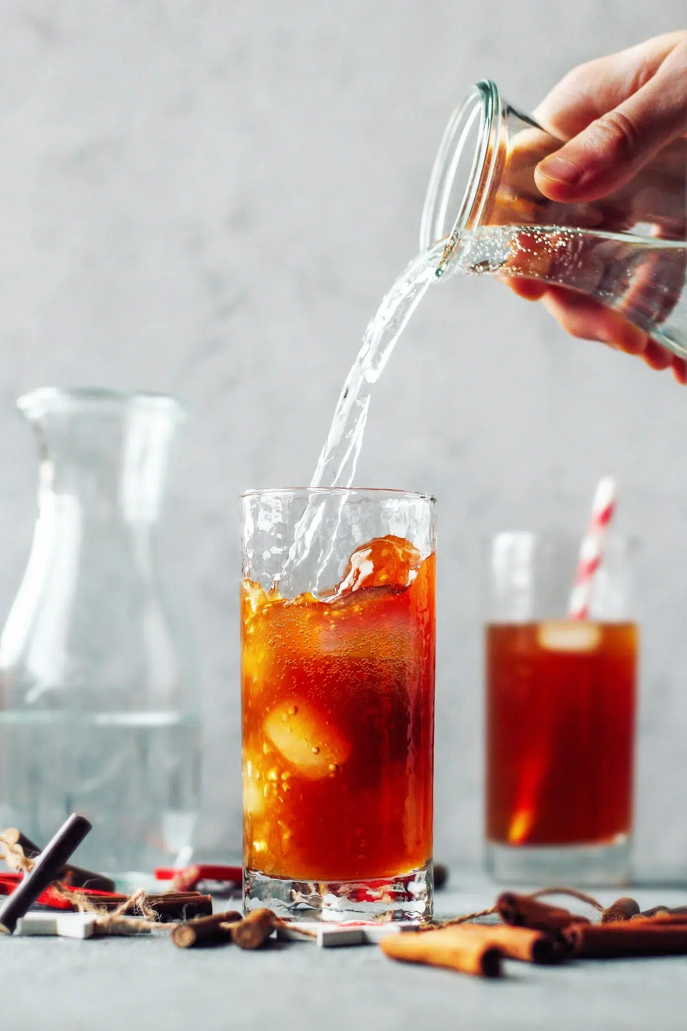 A person pouring iced tea- a refreshing beverage suitable for vegan diets, perfect for holiday gatherings and enjoyed year-round.