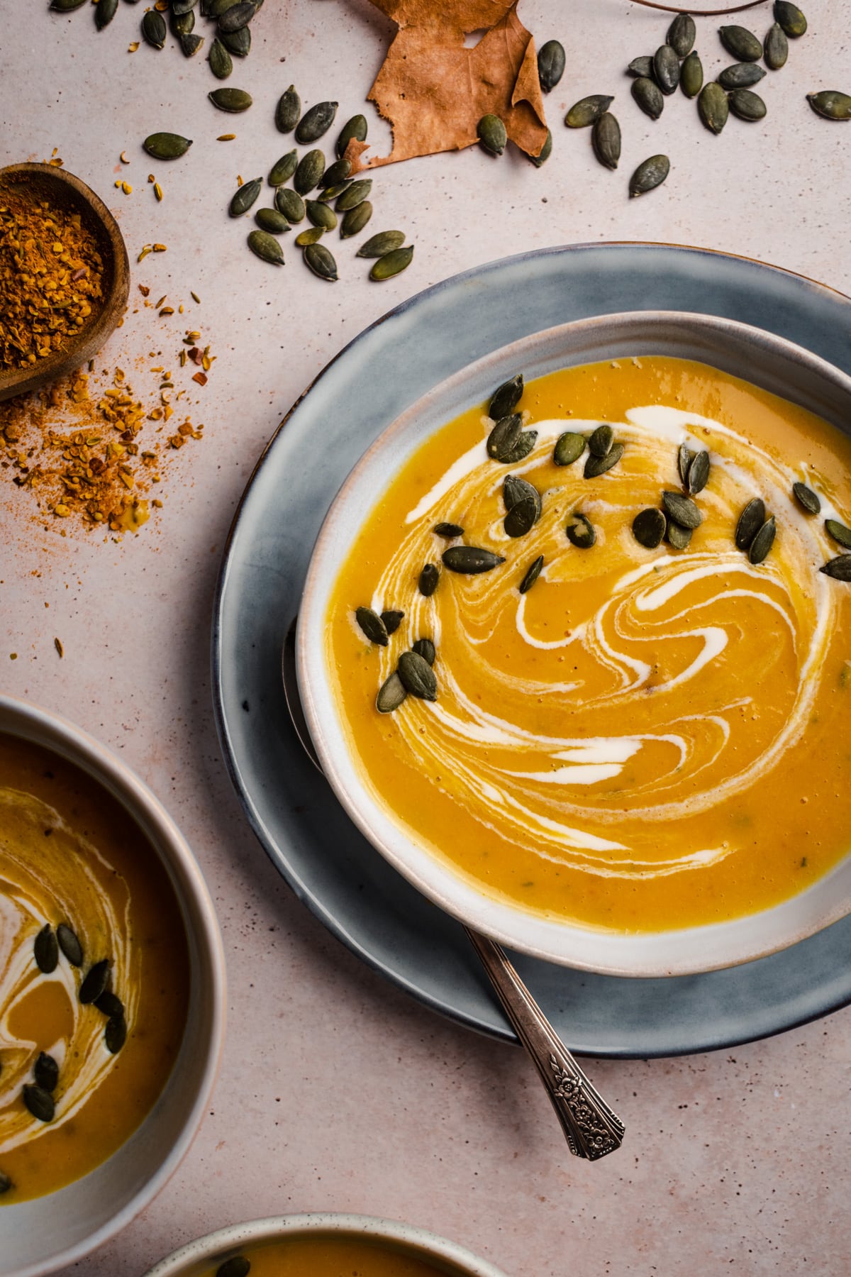 Large bowl of butternut squash soup with fresh spices on the side.