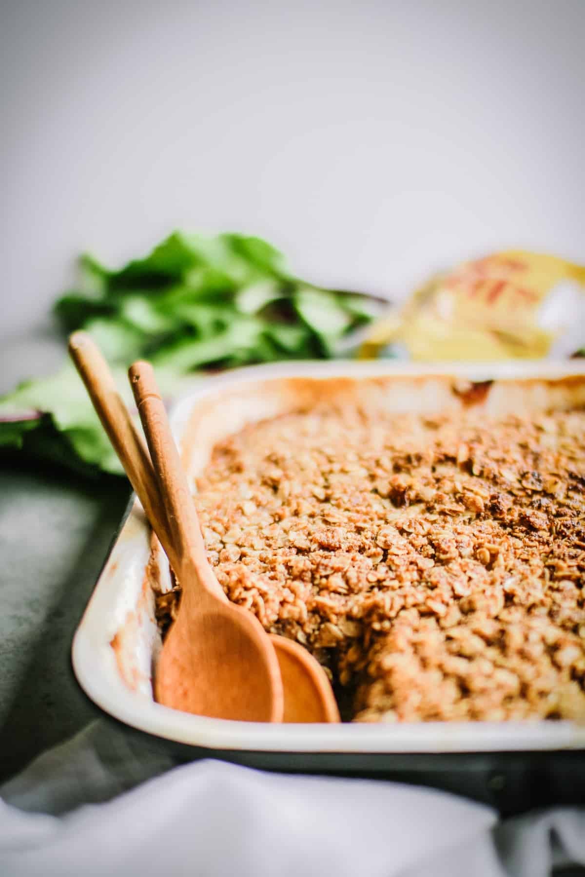Up close image of apple crisp with two wooden spoons. 