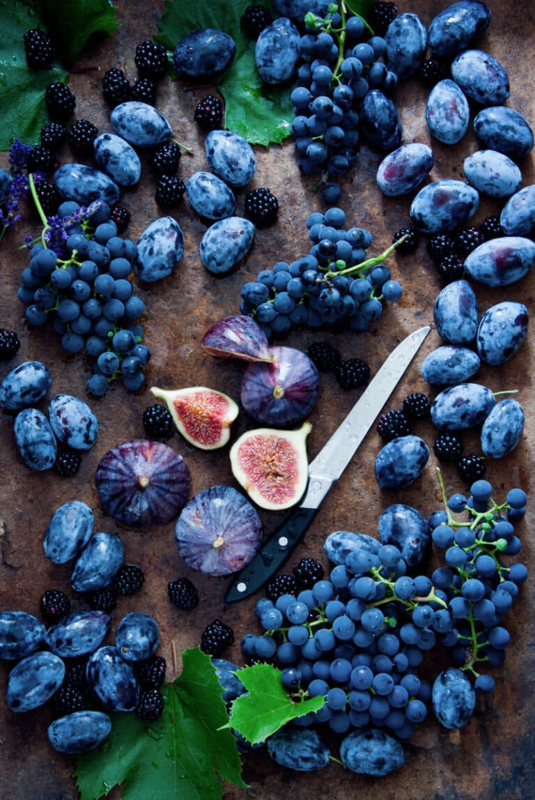 Blue grapes, blue berries, blue figs, blue honeysuckle and a knife.