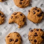 Dark orange pumpkin chocolate chip cookies on parchment paper.