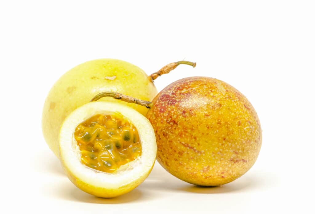 Two and a half passion fruits on a white surface.
