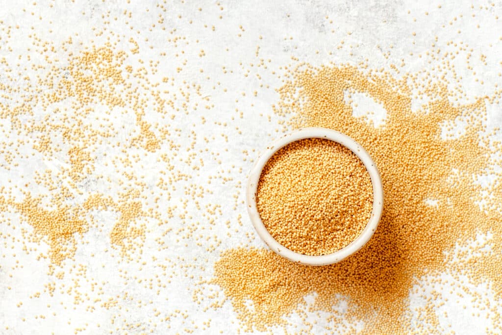 Small white overflowing bowl of golden yellow amaranth. 
