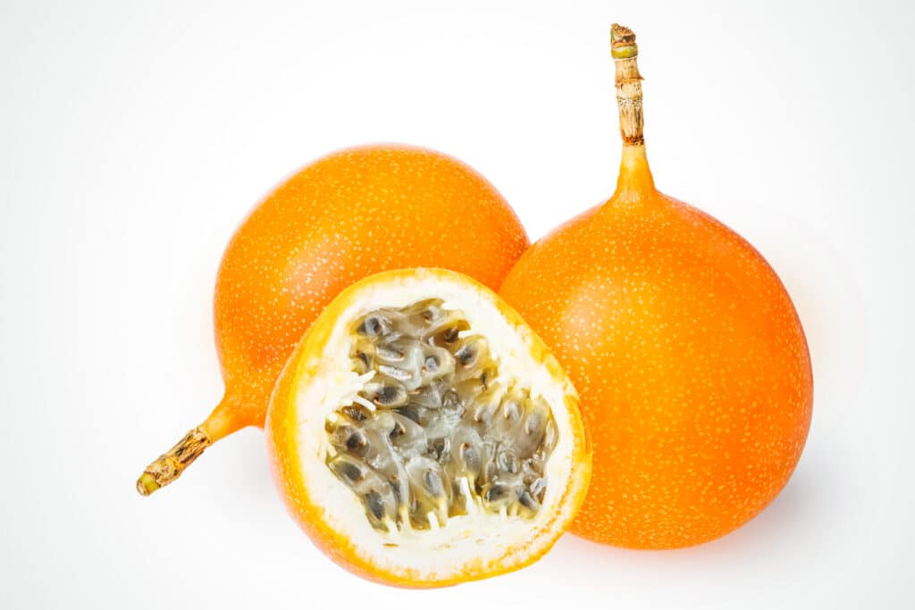 Two and a half sunshines yellow sugar fruit with one cut in half.