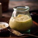 A small glass jar filled with avocado smoothie with a spoon of hemp seeds on the table.