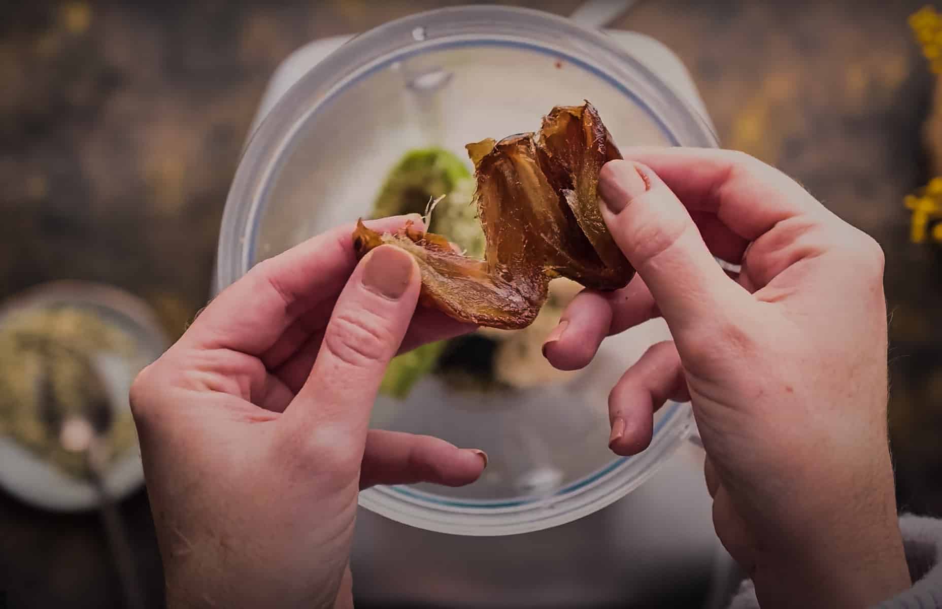 Close-up of hands separating a date over a blender.