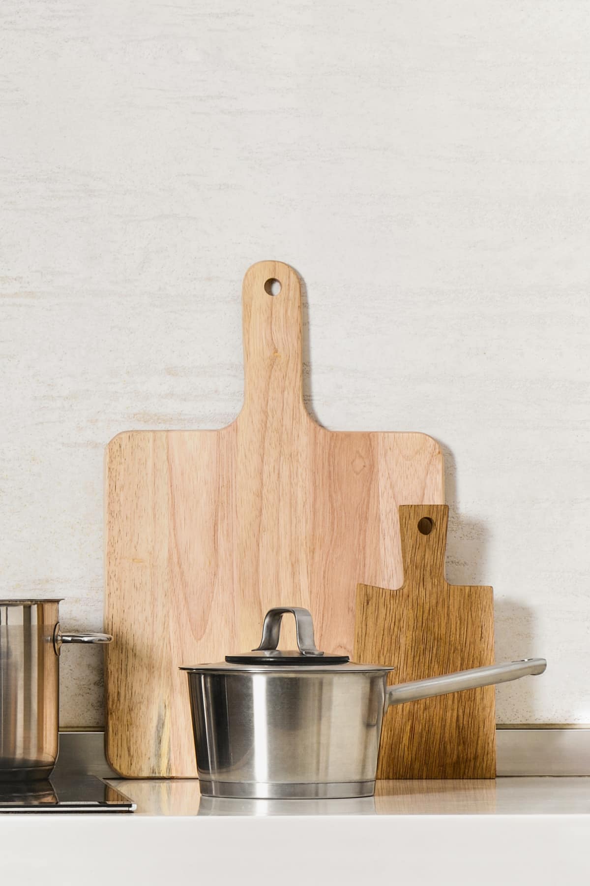 Stainless steel saucepan with two wooden cutting boards behind it. 