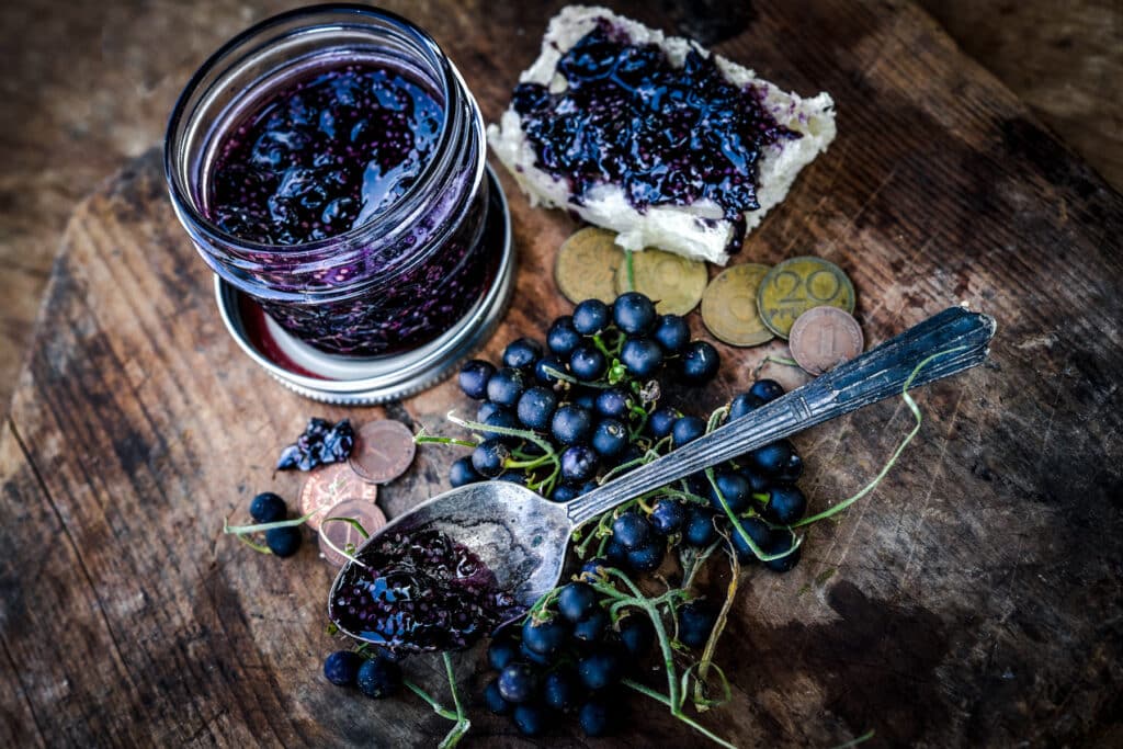 Black Schwartzenbeeren garden berries with green stems on a wooden table.