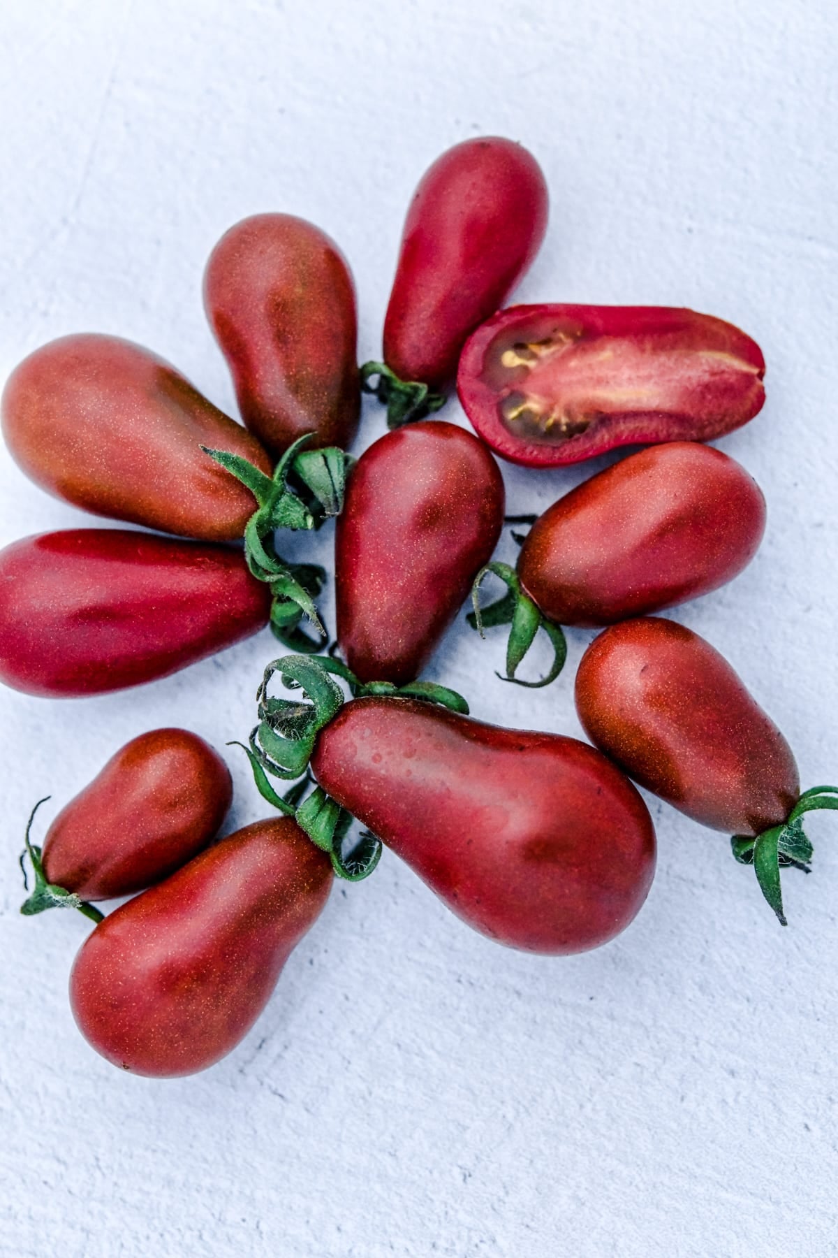 Chocolate pear tomato with deep red skin and subtle black speckles.