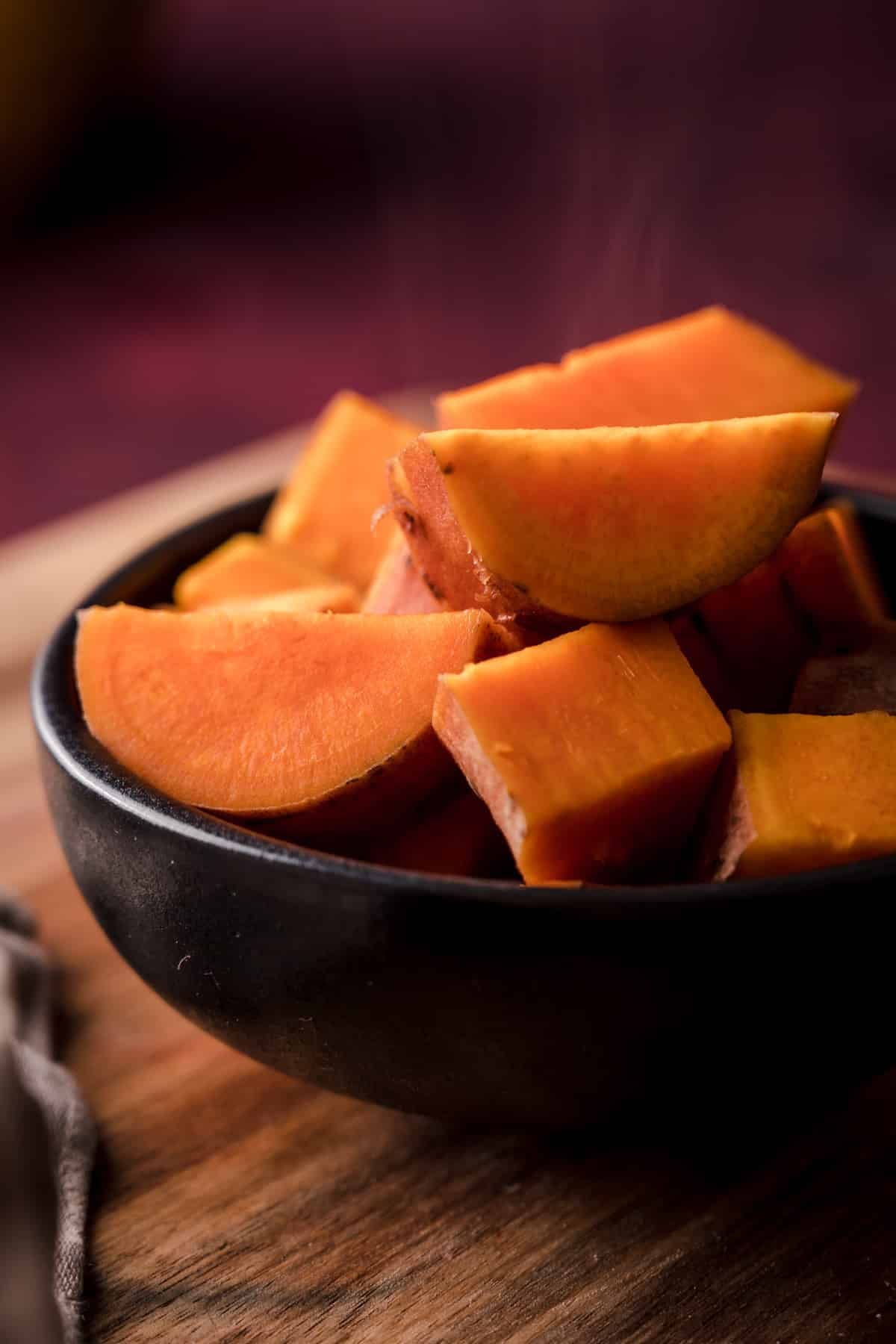 Cooked sweet potato chunks in a black bowl.