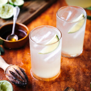 Two glasses of limeade and a juicer on the table.
