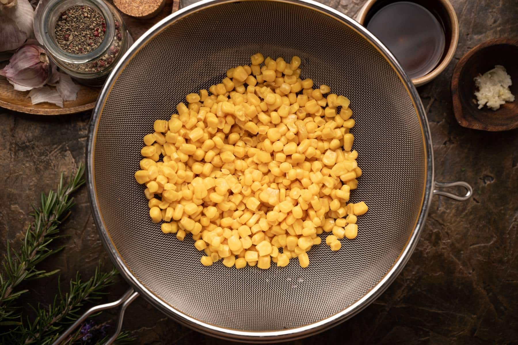 A colander filled with corn kernels being strained and rinsed.