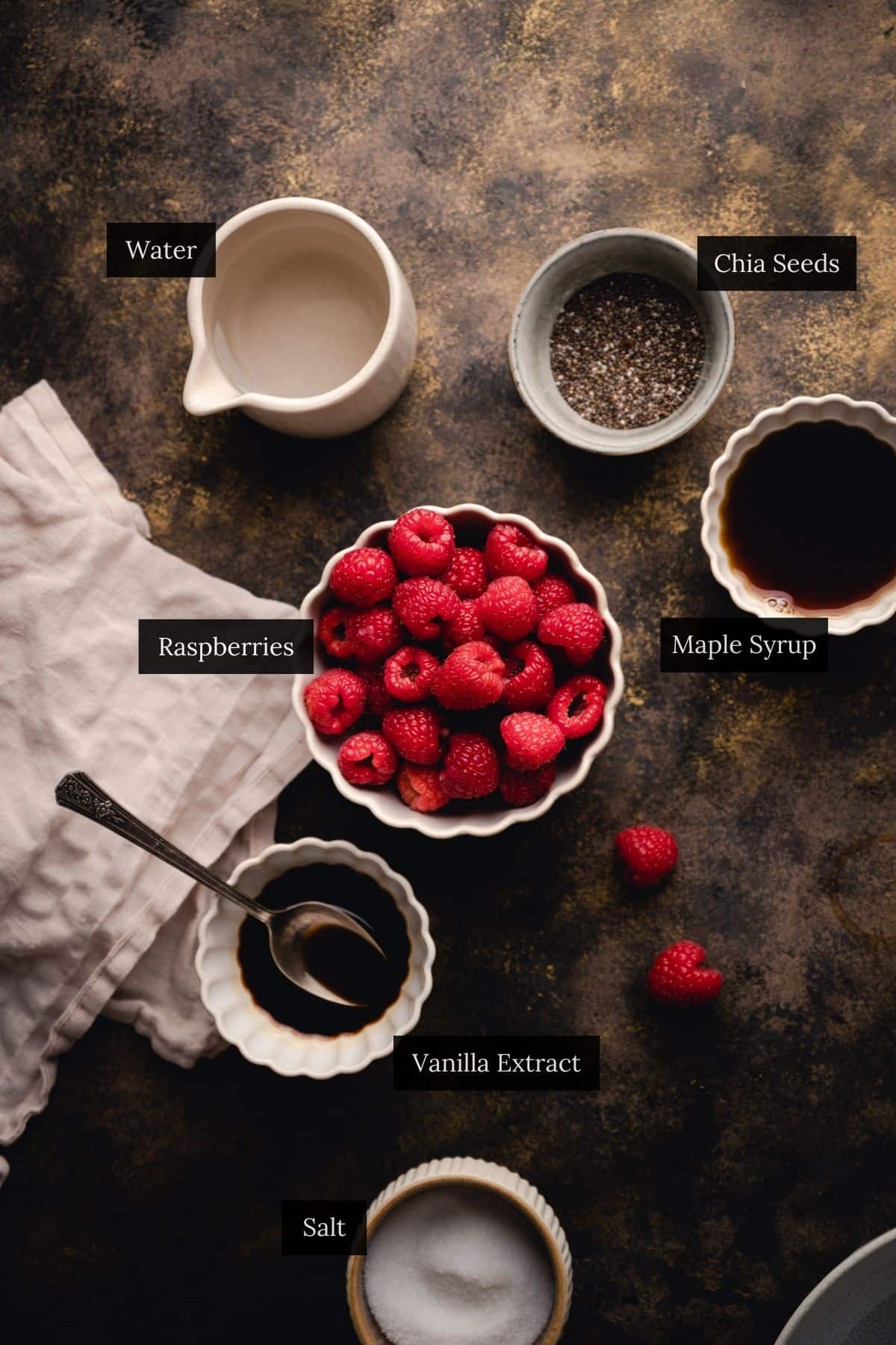 Bowls of ingredients including chia seeds, raspberries, maple syrup, and more.