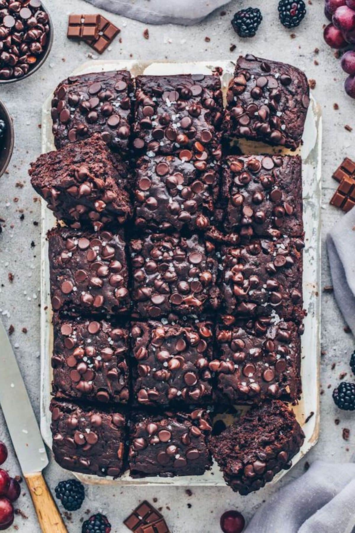 Tray of 15 vegan zucchini brownies with tons of chocolate chips on top.