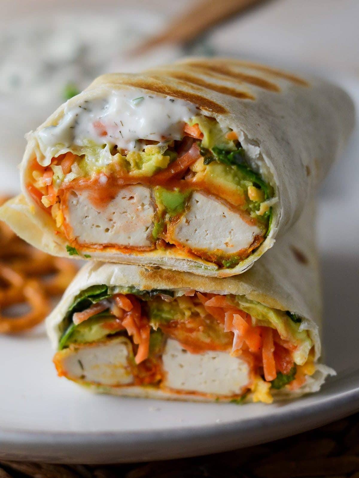 Two vegan tofu burritos on a plate.