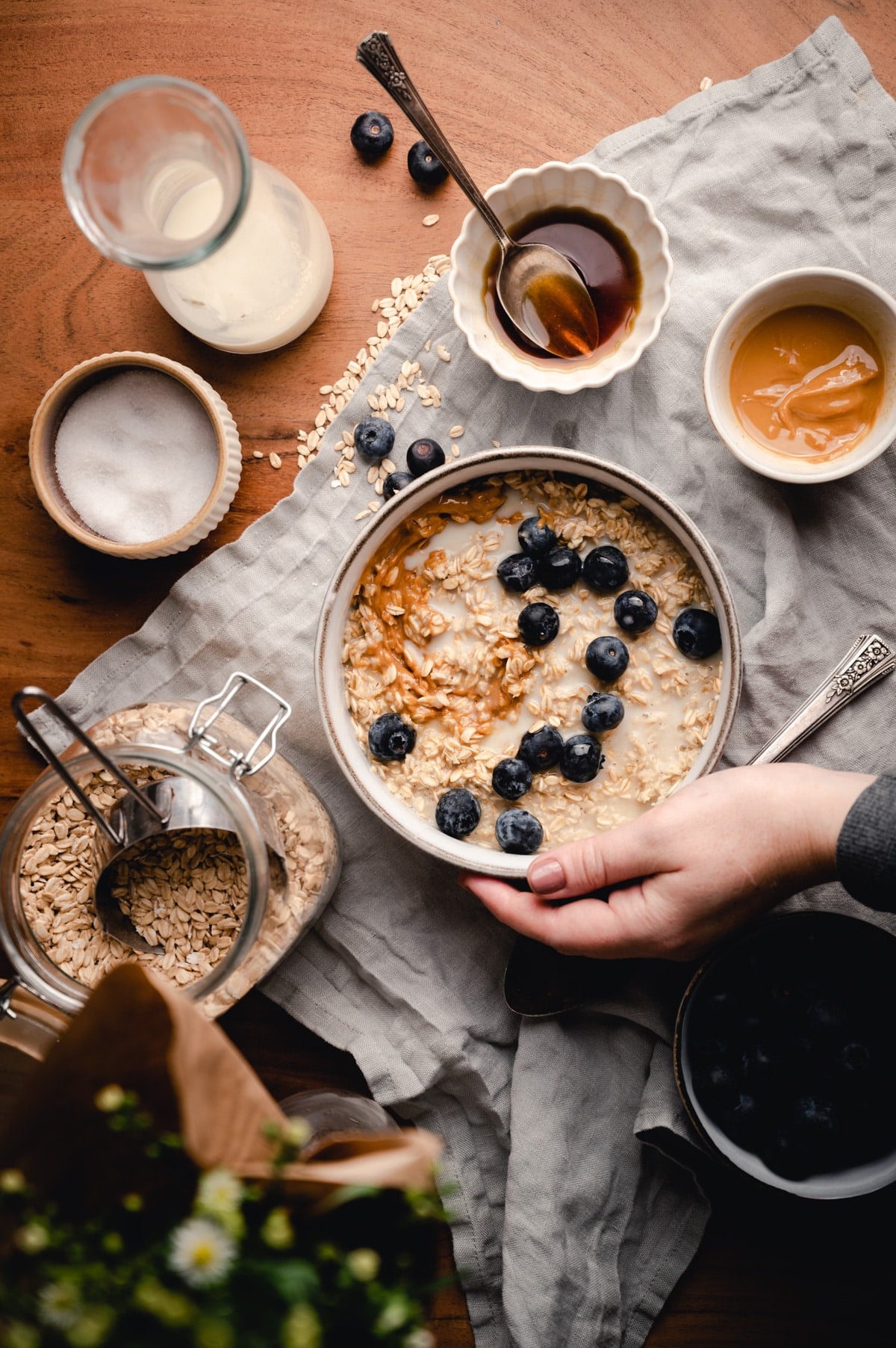 Woman picking up bowl of creamy oatmeal.