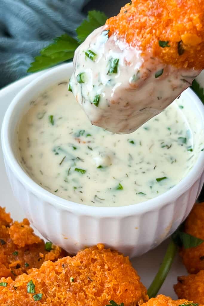 A vegan dipping sauce being dipped into a bowl of tofu chicken fingers.