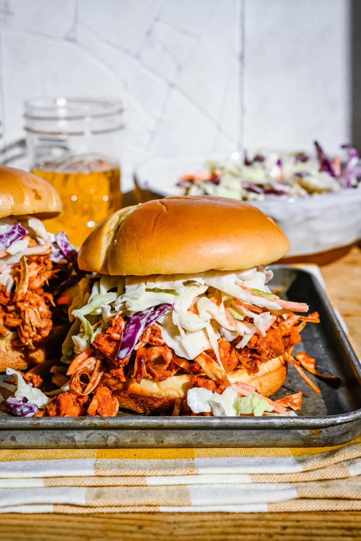 Overflowing pulled jackfruit burgers with vegan slaw on top.