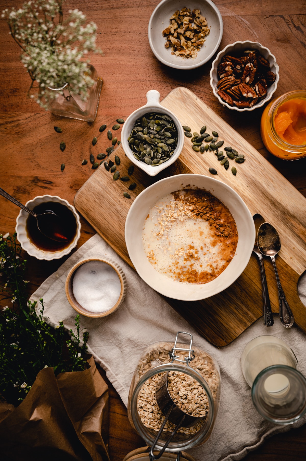 Large ceramic bowl filled with pumpkin oatmeal ingredients with oat milk poured on top.