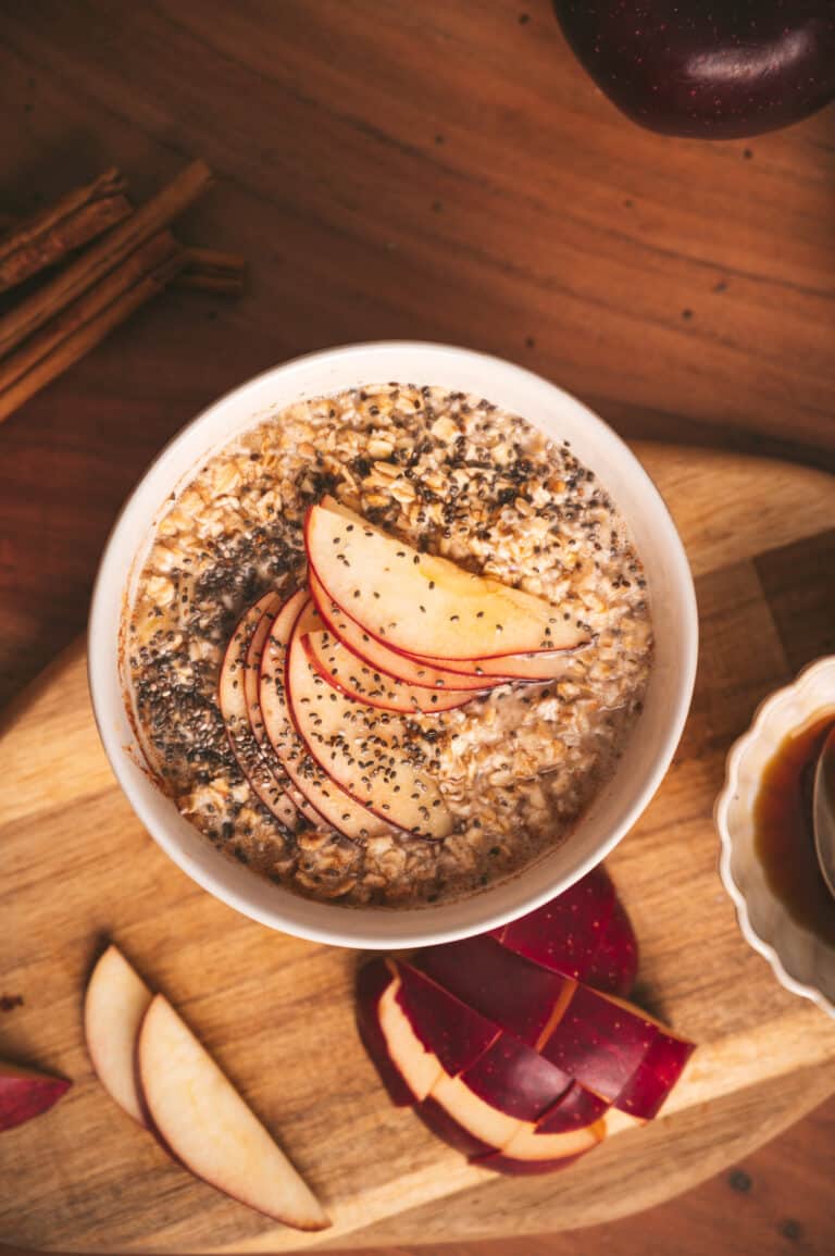 Flatlay photo of apple cinnamon oatmeal with sliced apples fanned out on top.