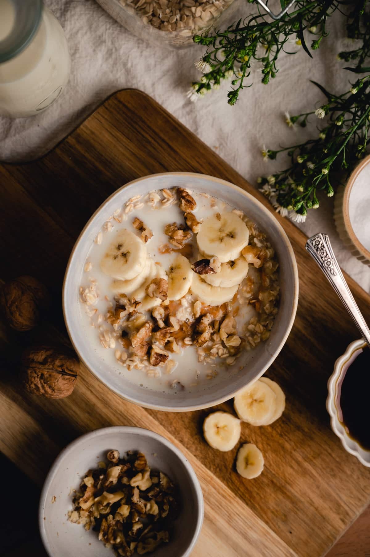 Flat lay of oatmeal with banana on a wooden cutting board.