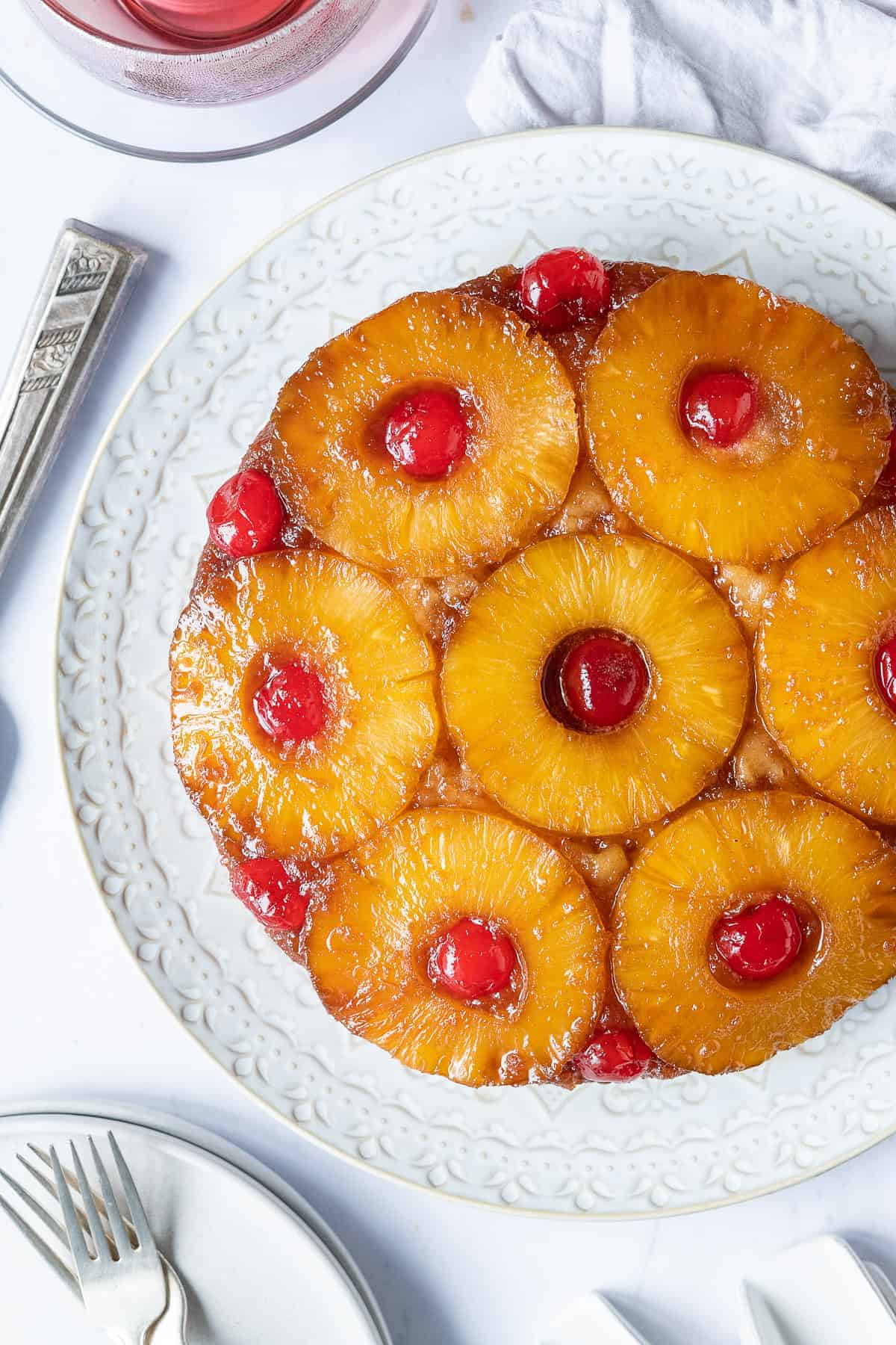 Pineapple upside-down cake topped with caramelized pineapple slices and cherries.