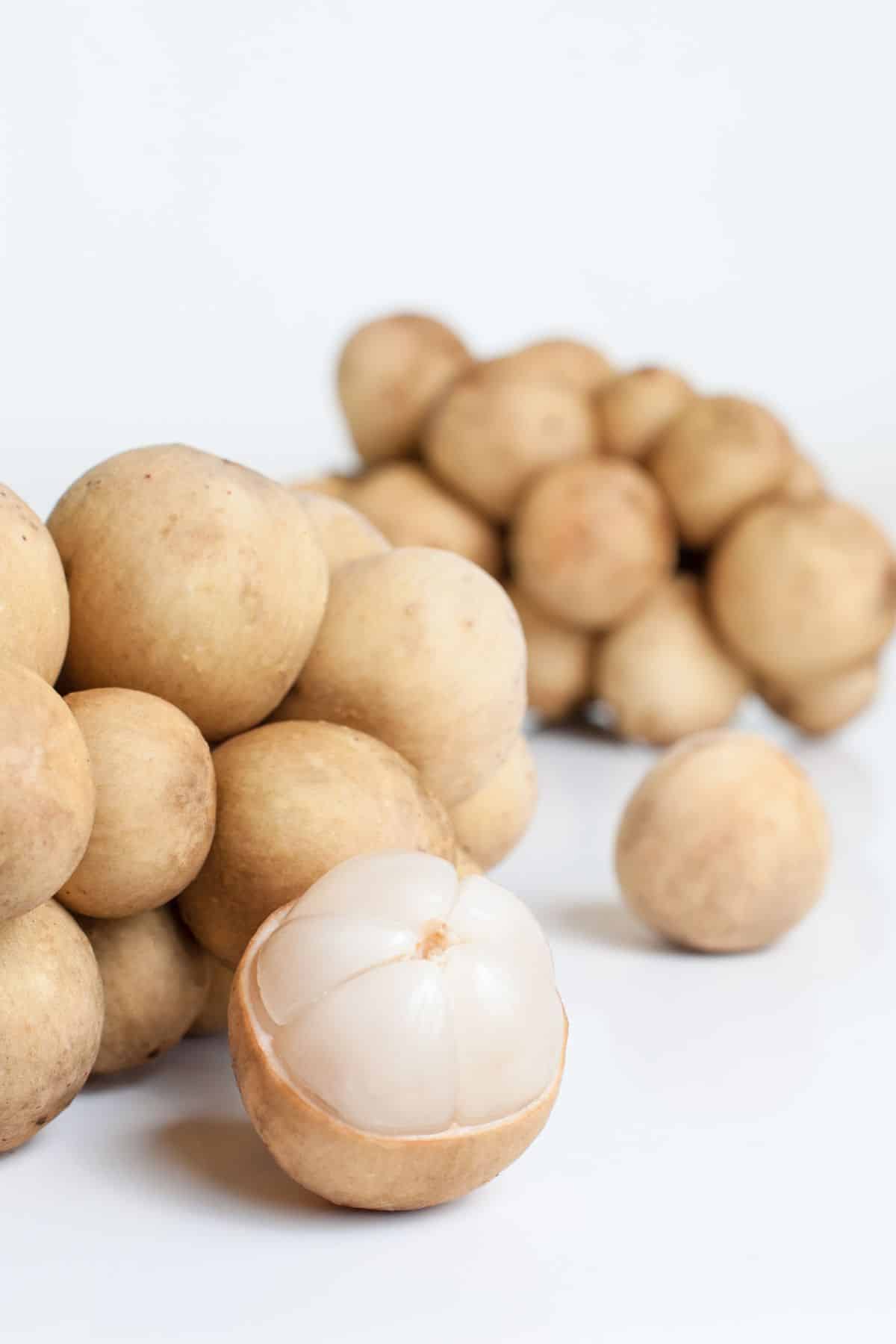 Pile of cream skinned longsat on a white counter.