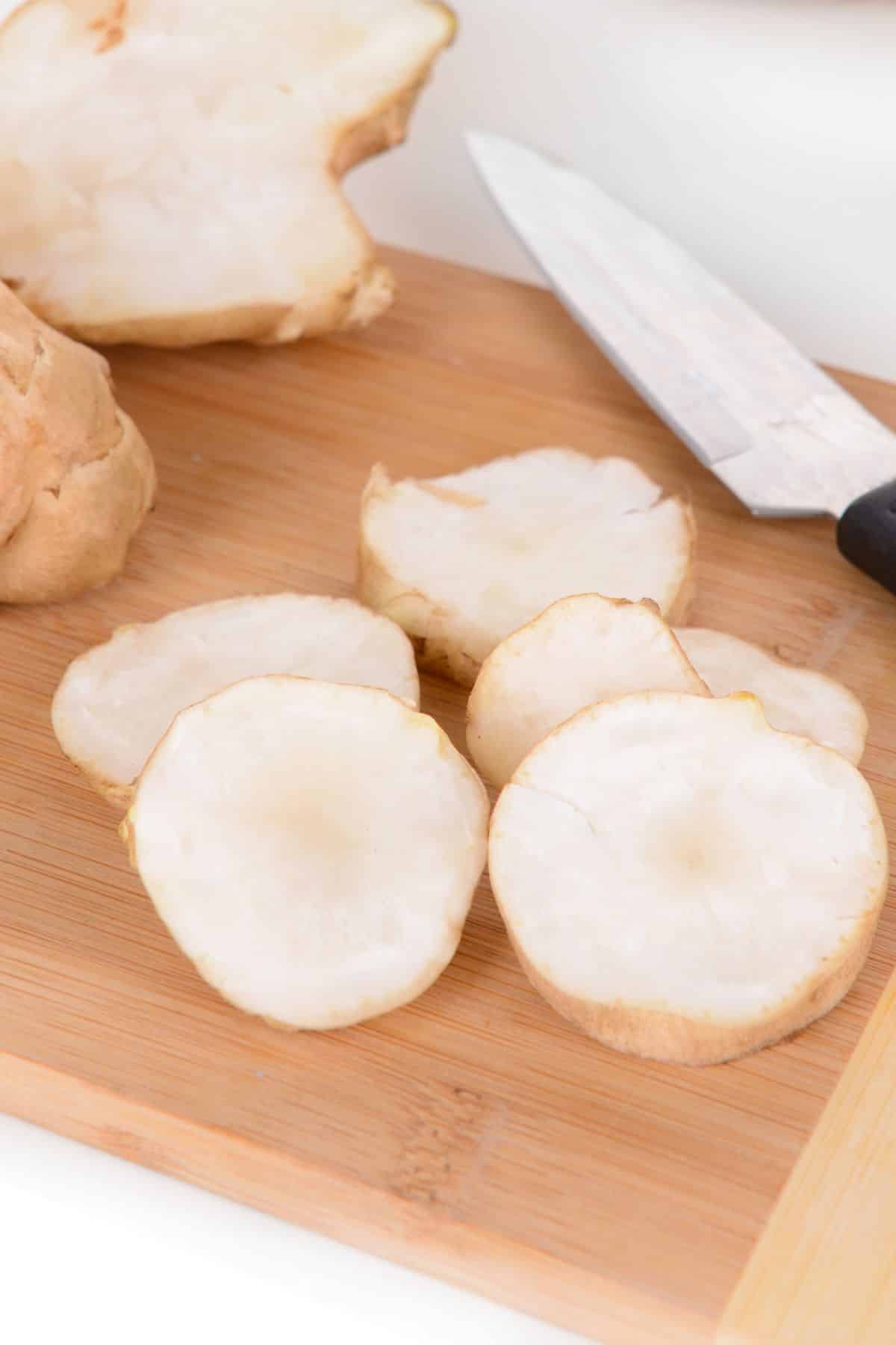 Freshly chopped sunchoke on a wooden cutting board.
