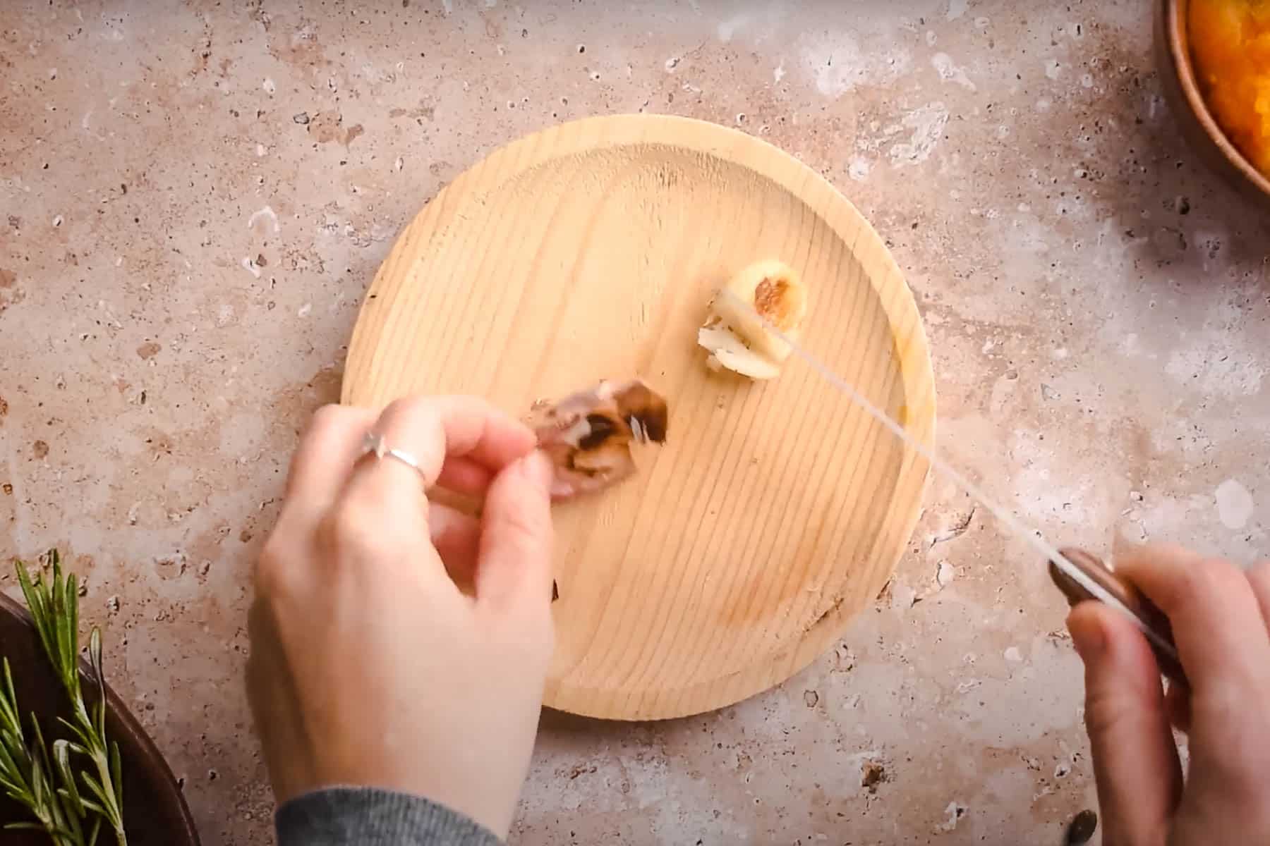 A person removing garlic skin from roasted garlic cloves.