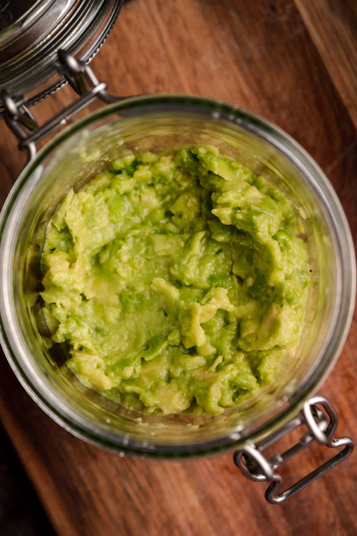 Close up of smashed avocado in a glass jar.