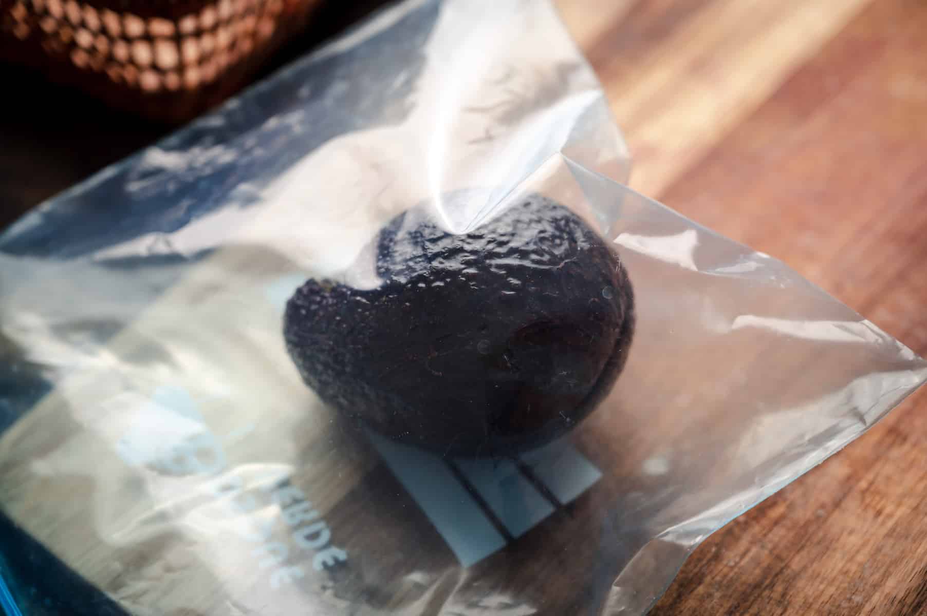 A whole avocado frozen in a plastic ziplock bag.