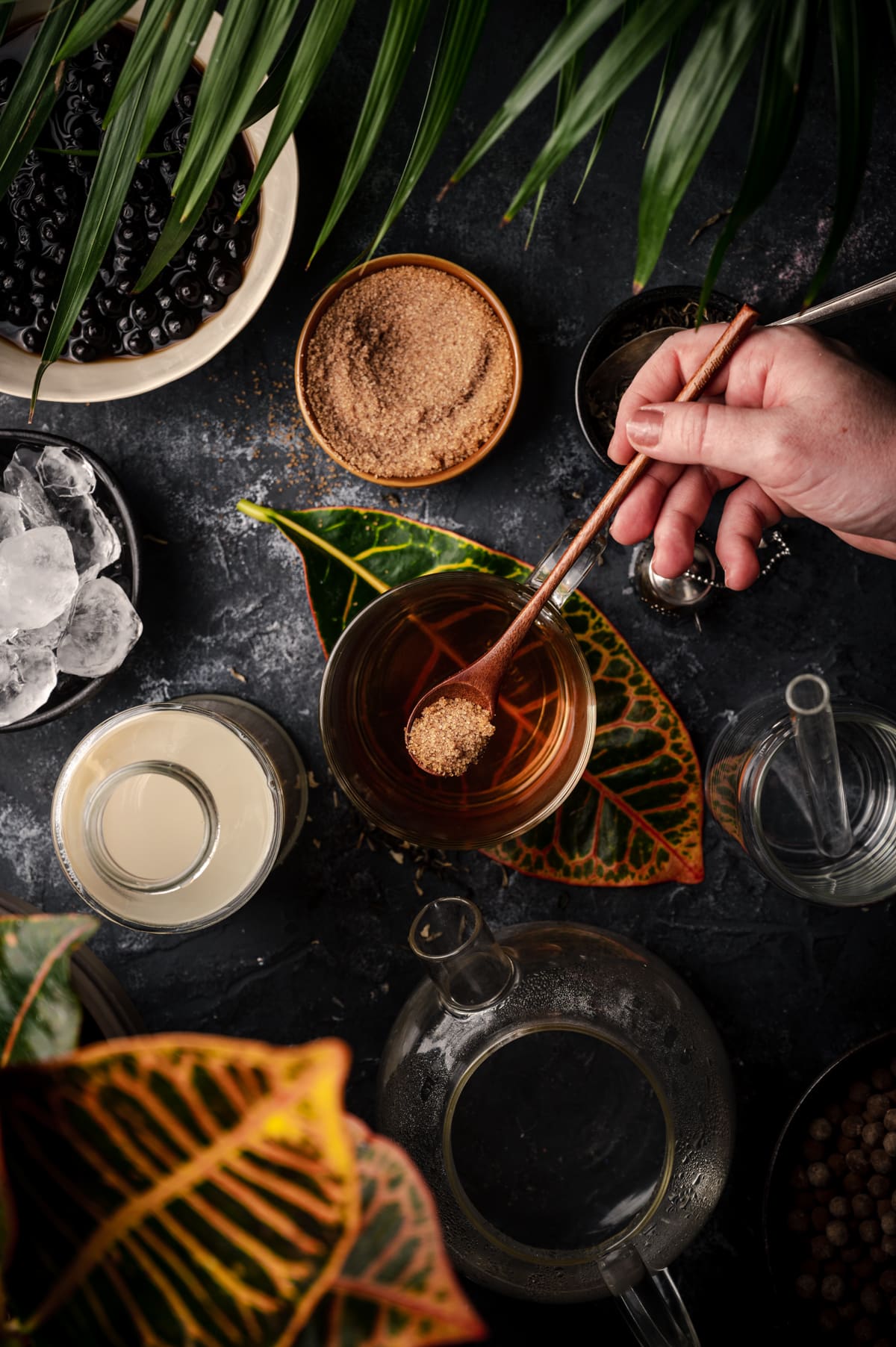 Woman scooping raw cane sugar into the brewed jasmine tea.