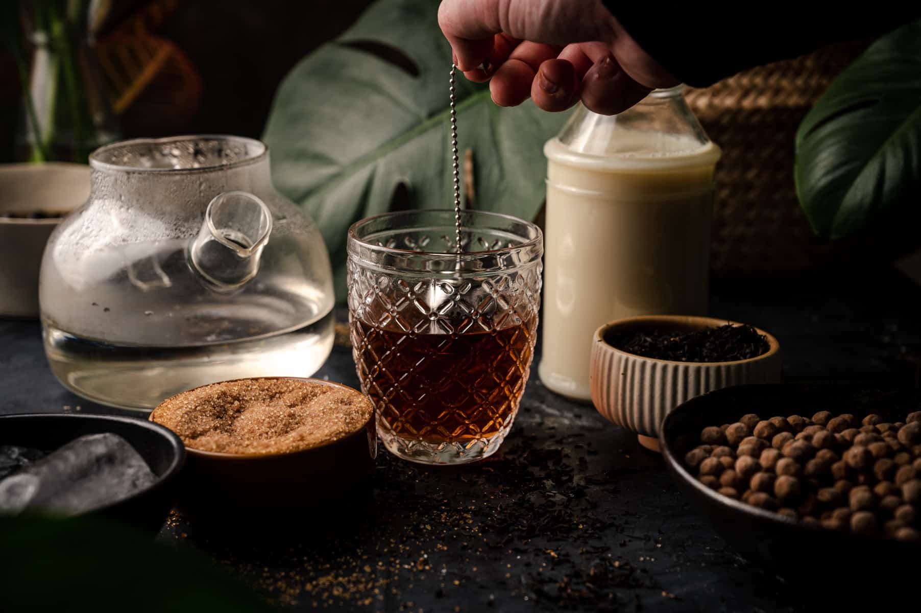 Woman dipping metal tea infuser into crystal glass of hot water.