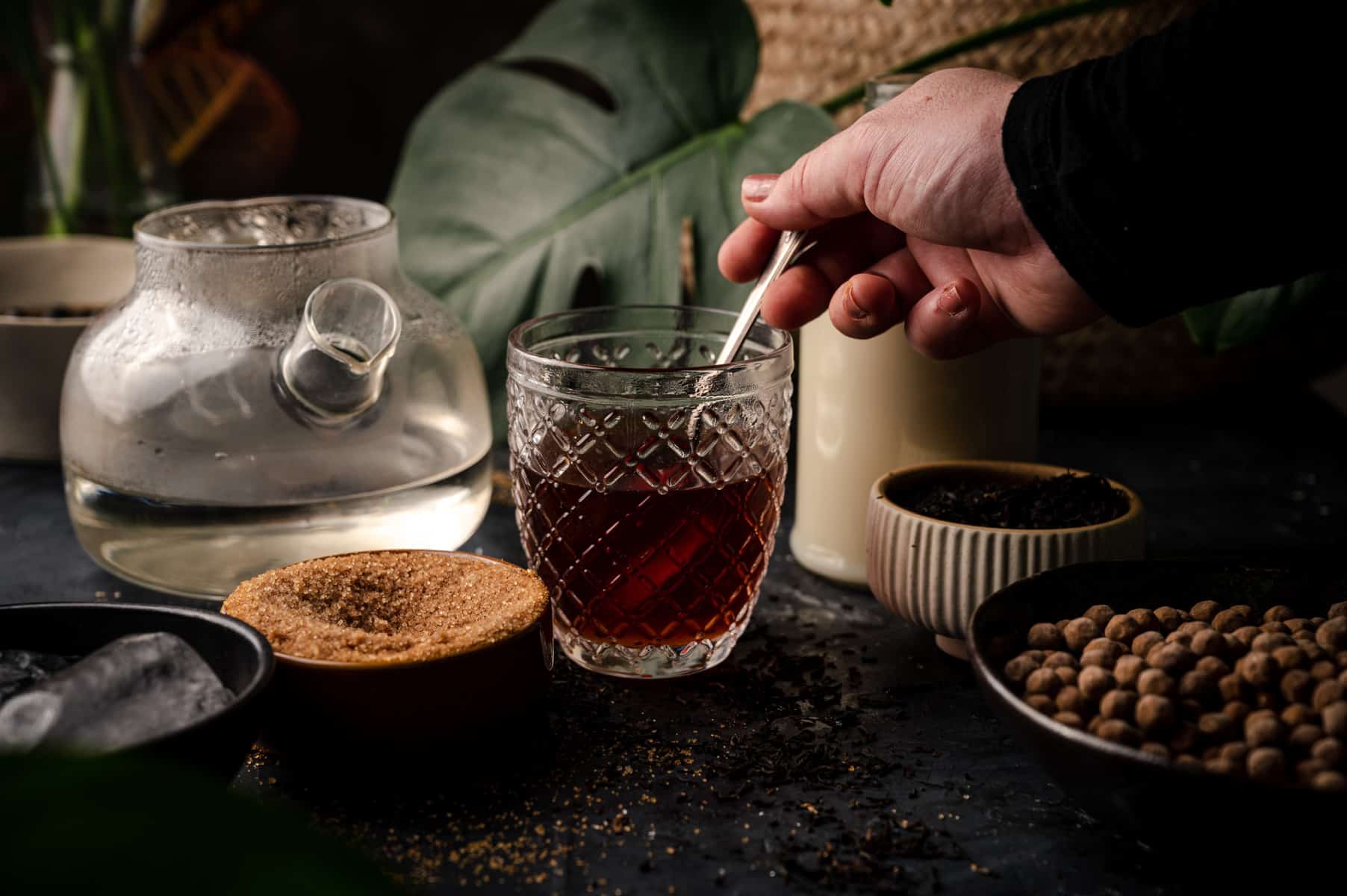 Woman's hand stirring in can sugar into oolong tea.