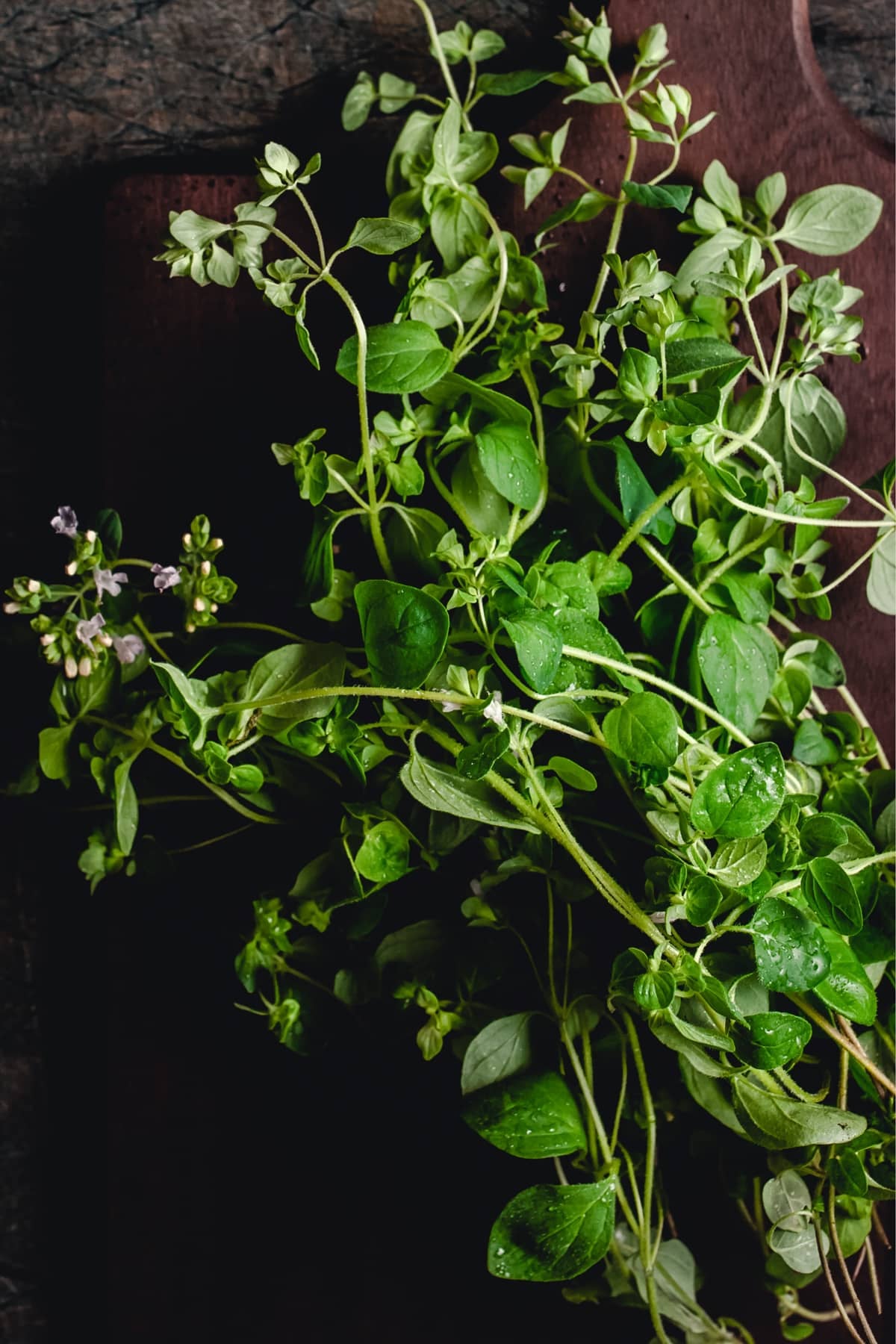 A bunch of fresh herbs on a cutting board.