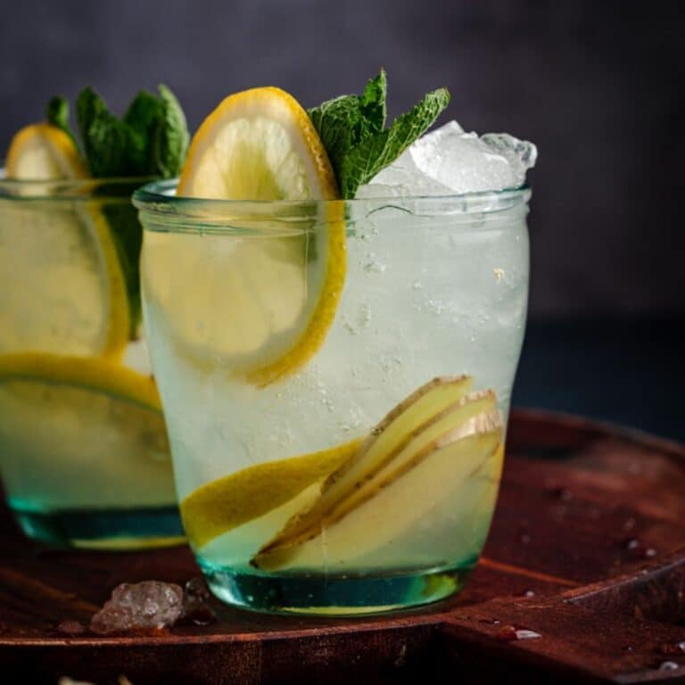 Two glasses of lemonade with ice and mint leaves.