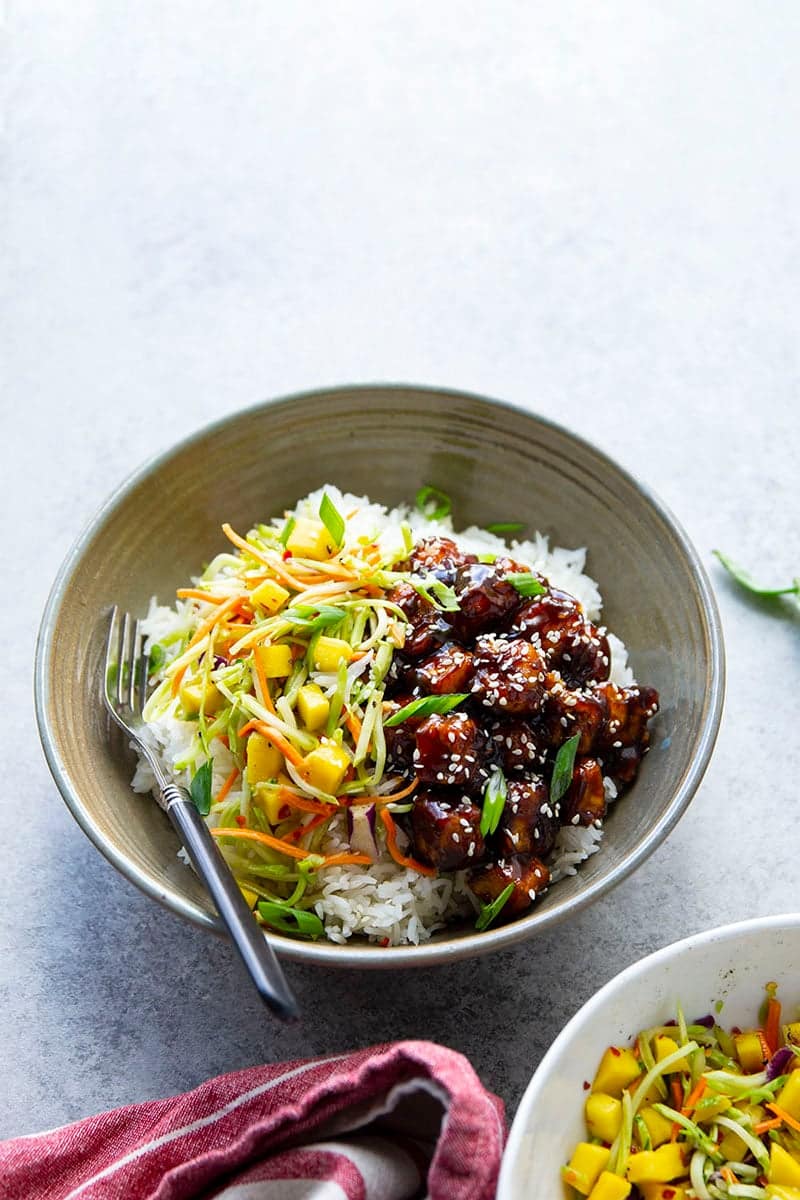 A bowl of rice and a bowl of meat on a table.