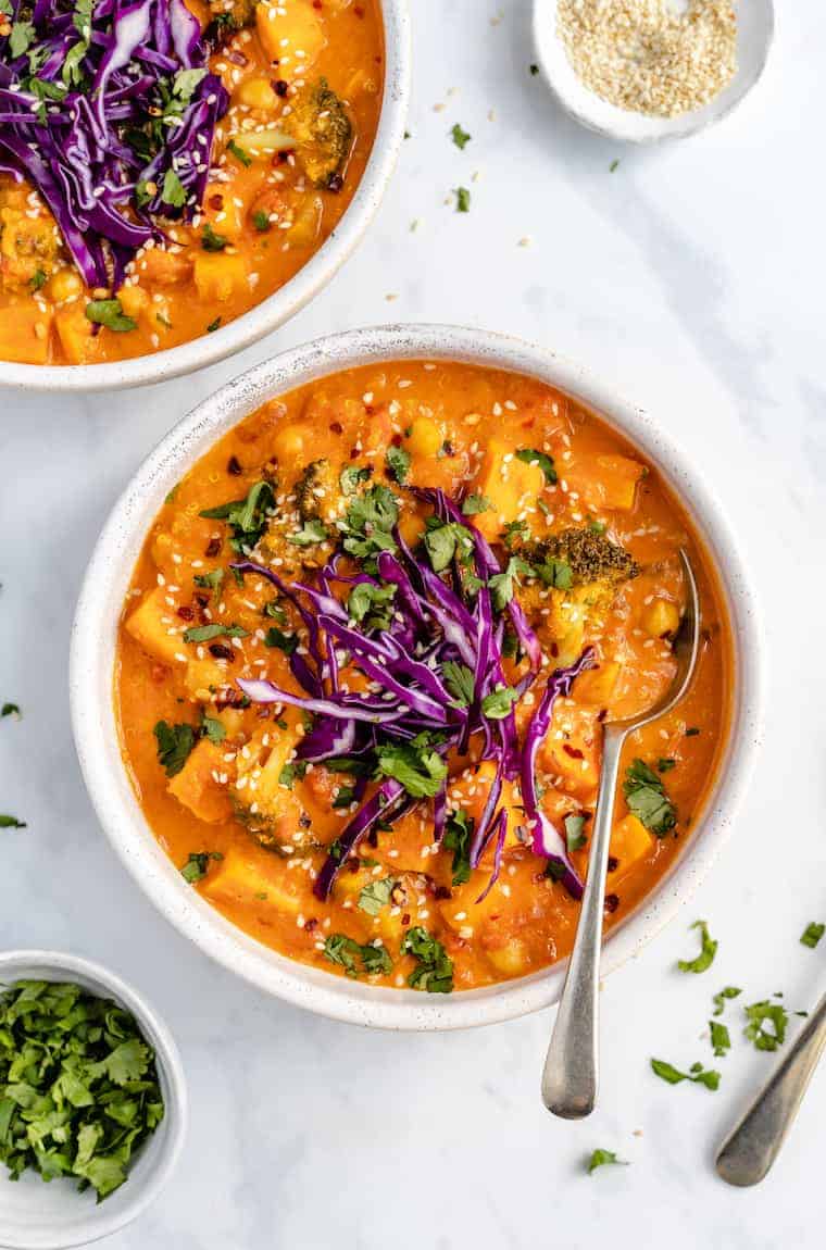 Two bowls of red curry with broccoli and slaw.
