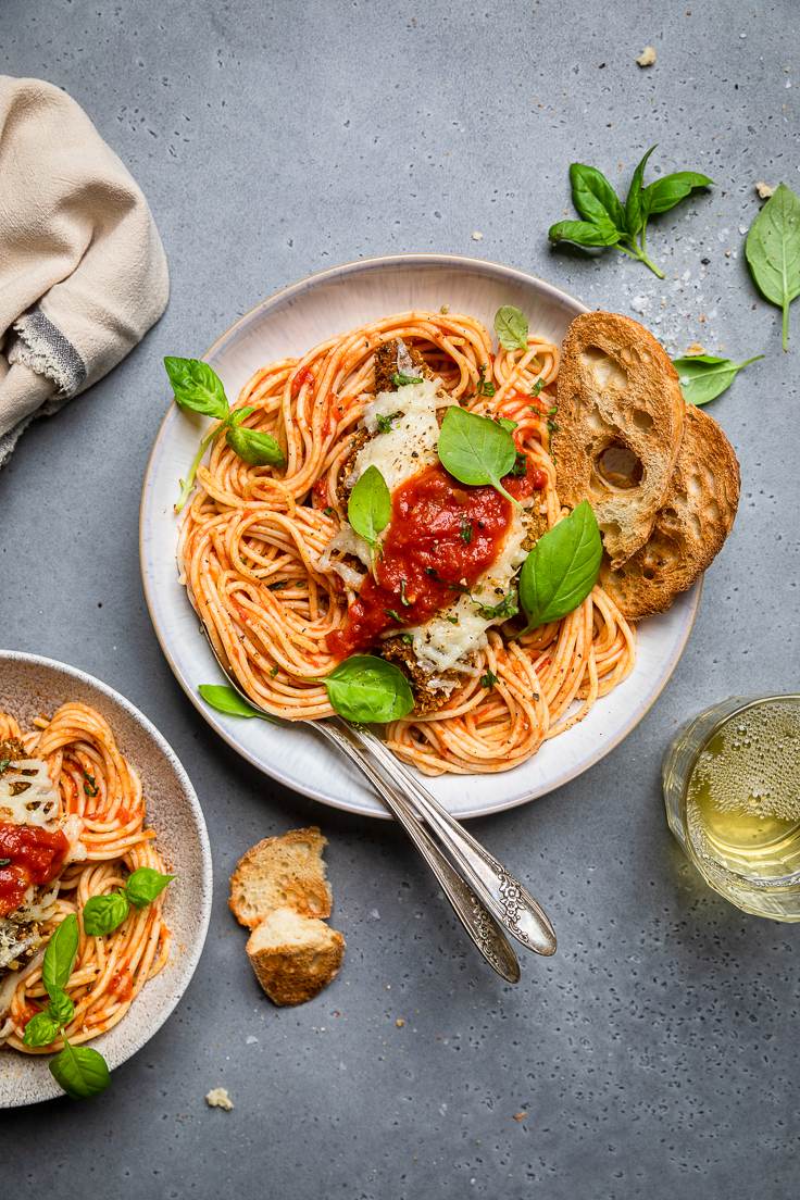 Spaghetti with tomato sauce and bread on a gray background.