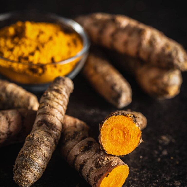 Tumeric powder in a bowl on a black background.