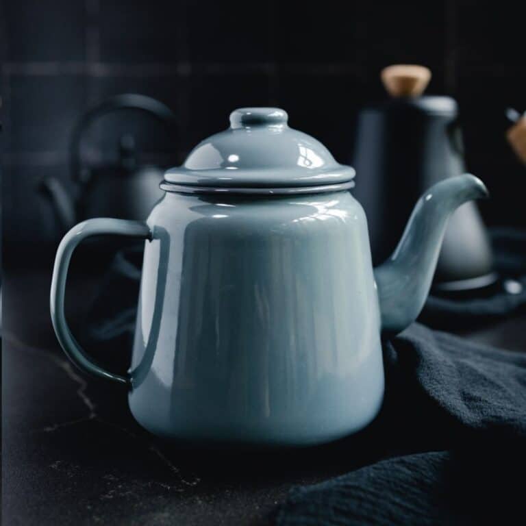 A blue enamel teapot, crafted with non-toxic materials, sits on a dark counter.