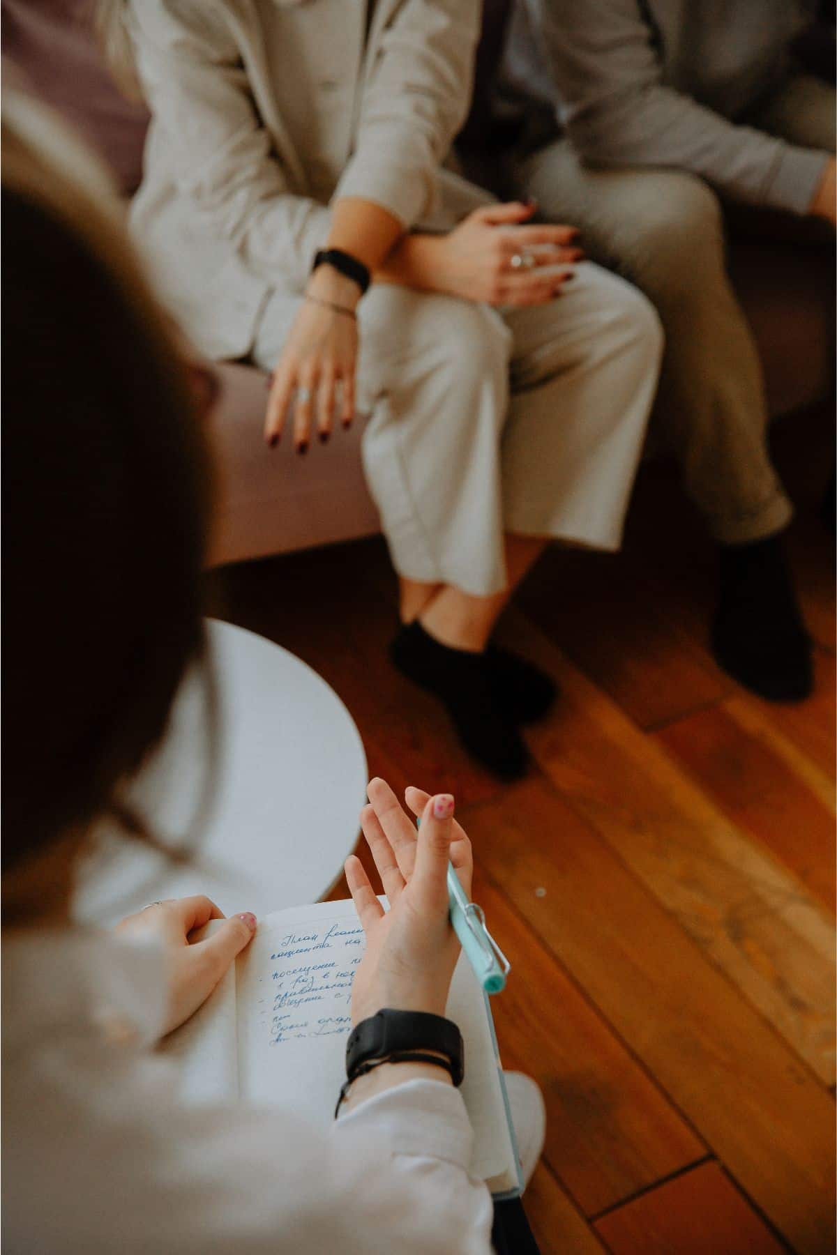 A group of people sitting around a table and writing in a notebook.