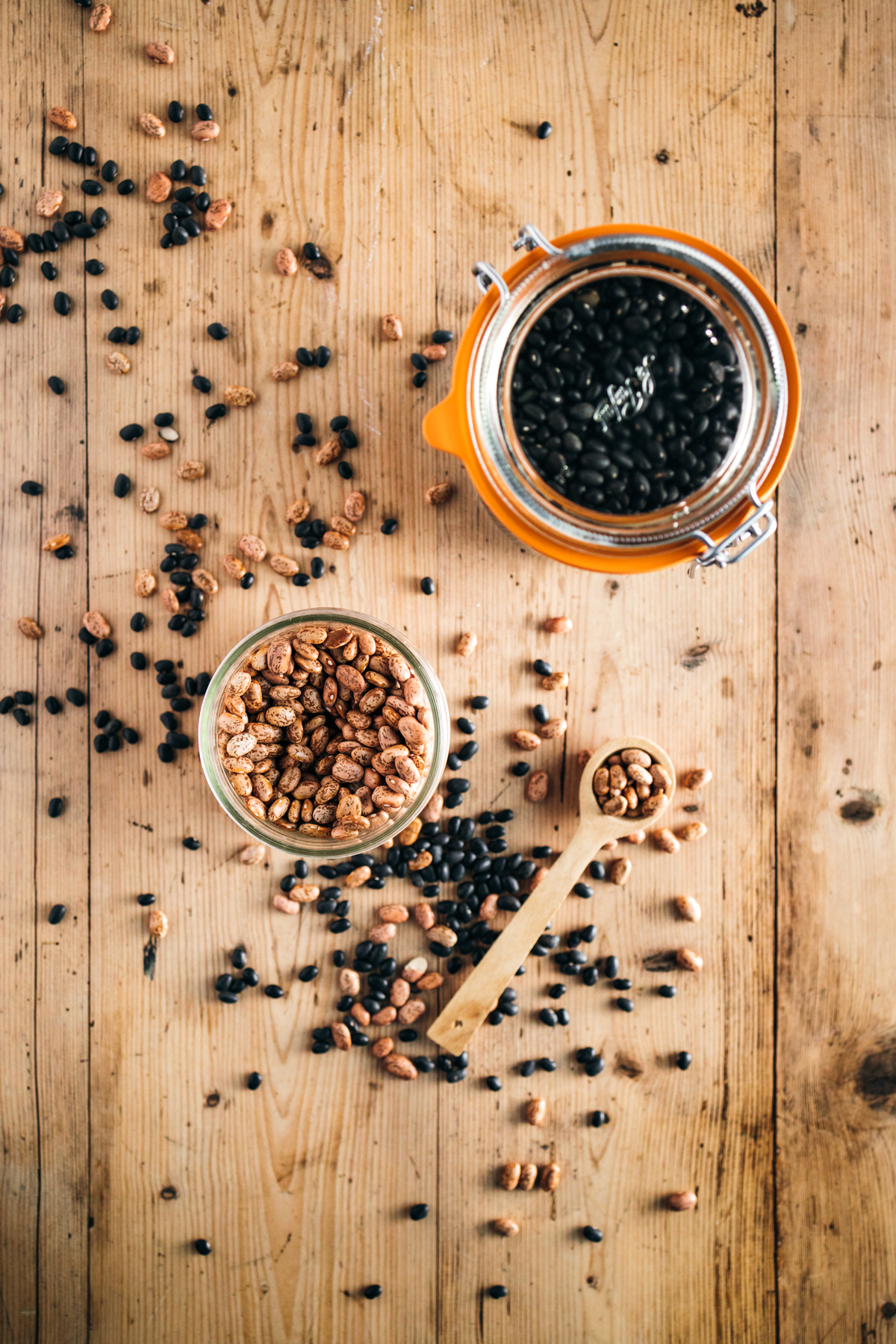 Black beans in a jar and a spoon on a wooden table.