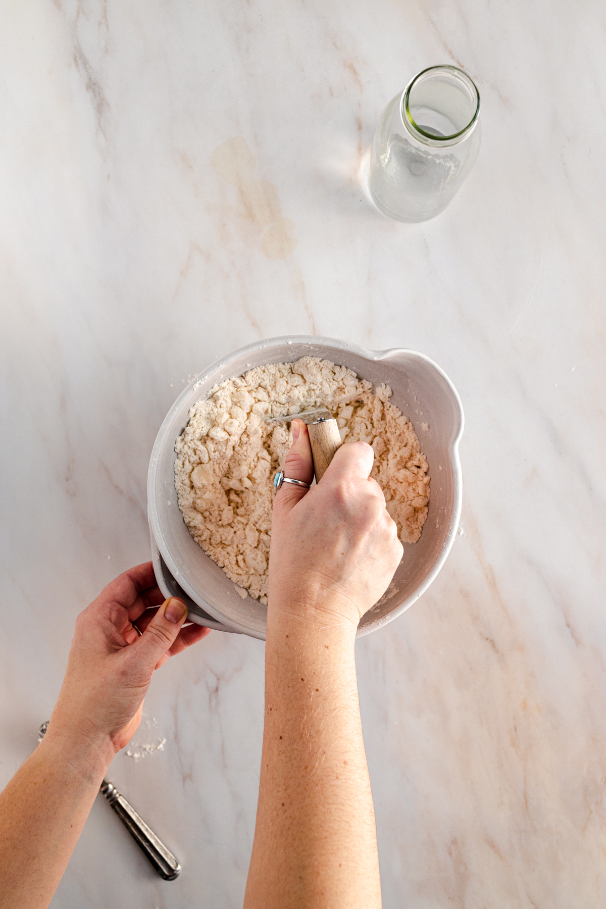 A person is sifting flour into a bowl.