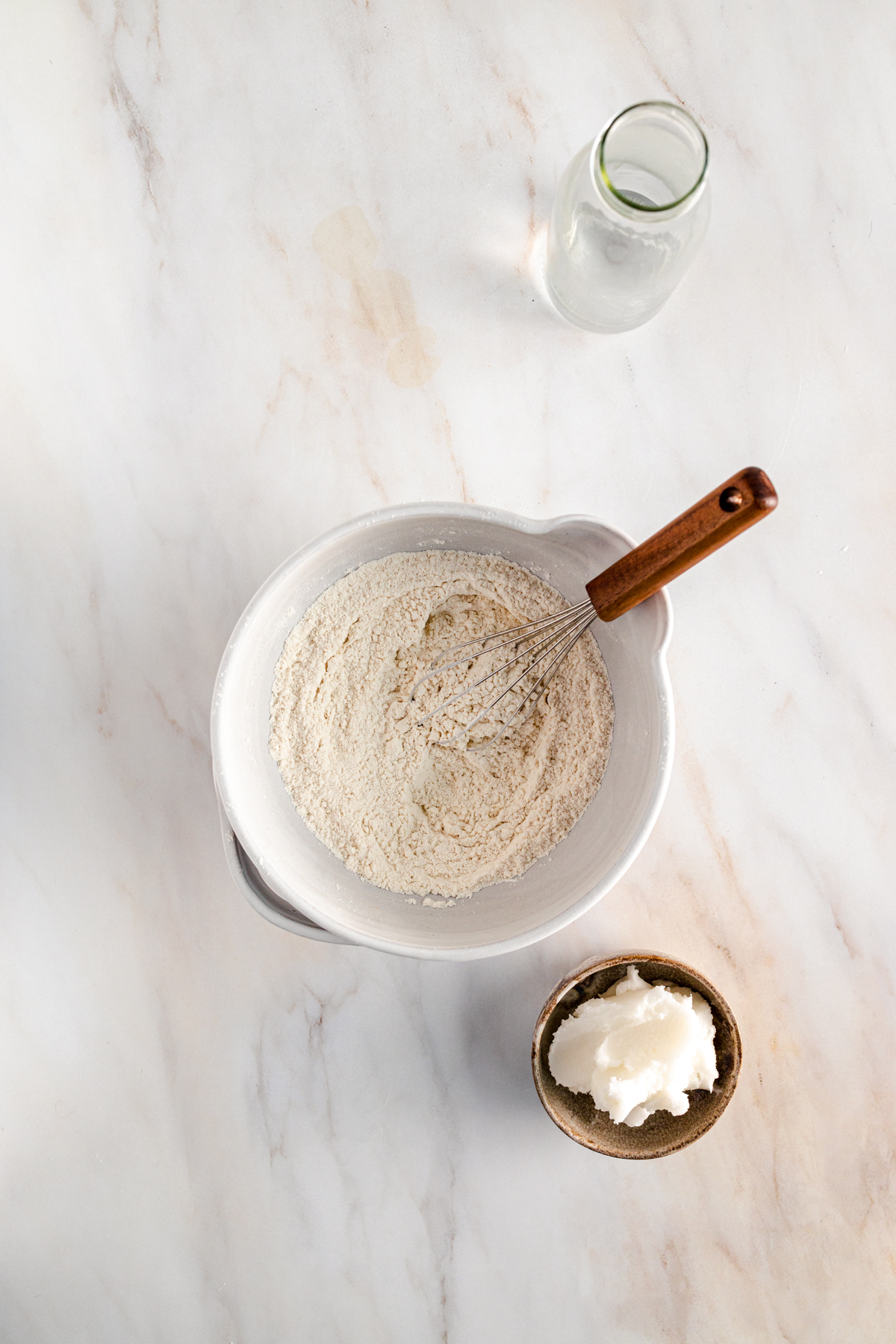 A bowl of flour and a spoon on a marble table.