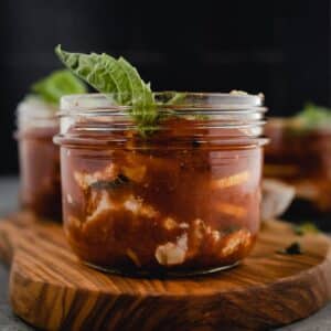 Glass jar with homemade lasagna in it with fresh basil on top.