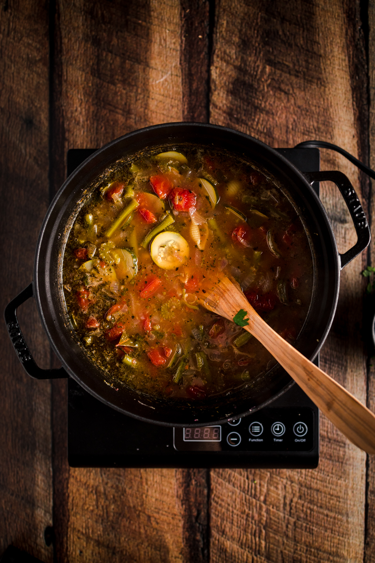 A pot of soup with a wooden spoon on a wooden table.