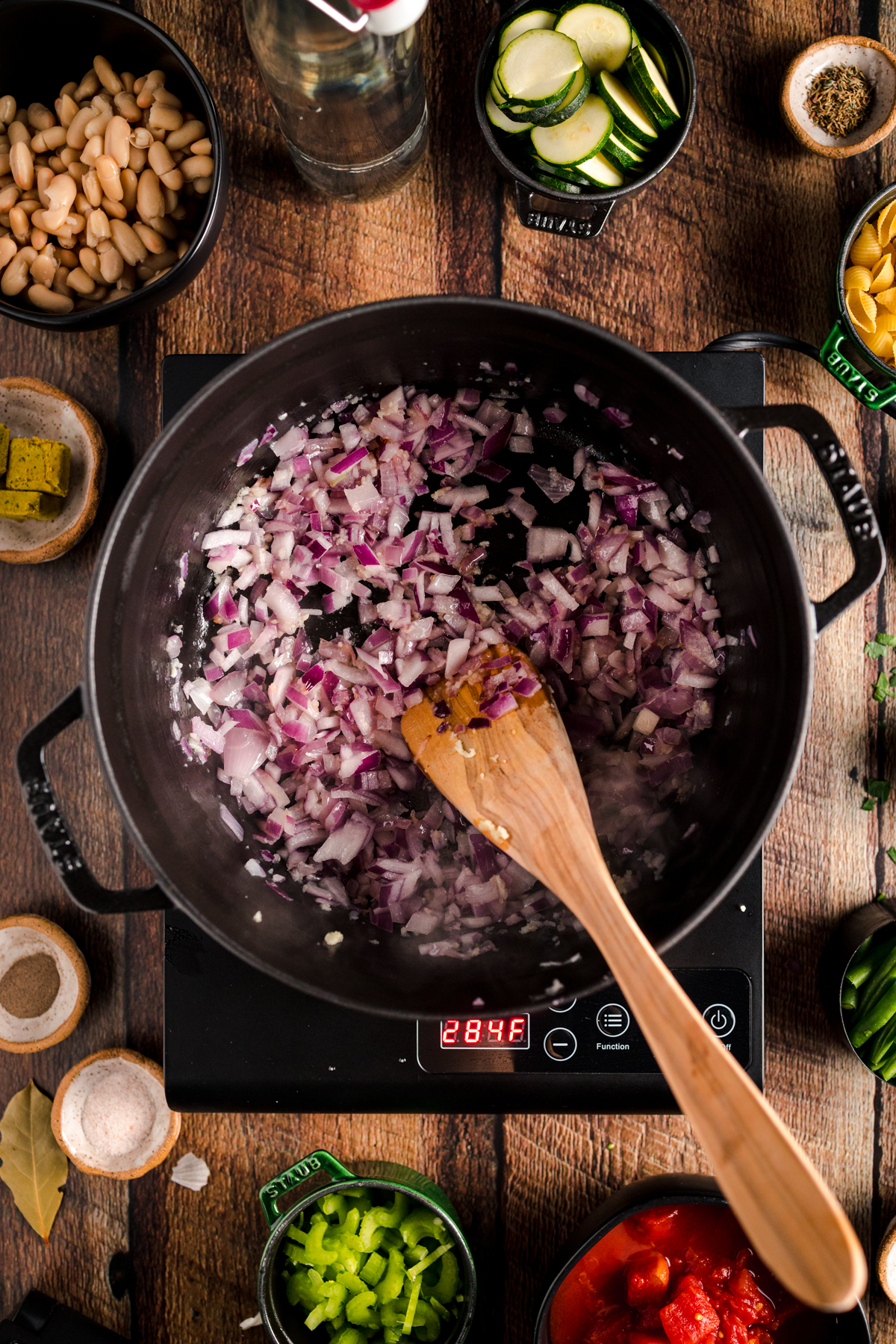 A pot with vegetables and a wooden spoon in it.
