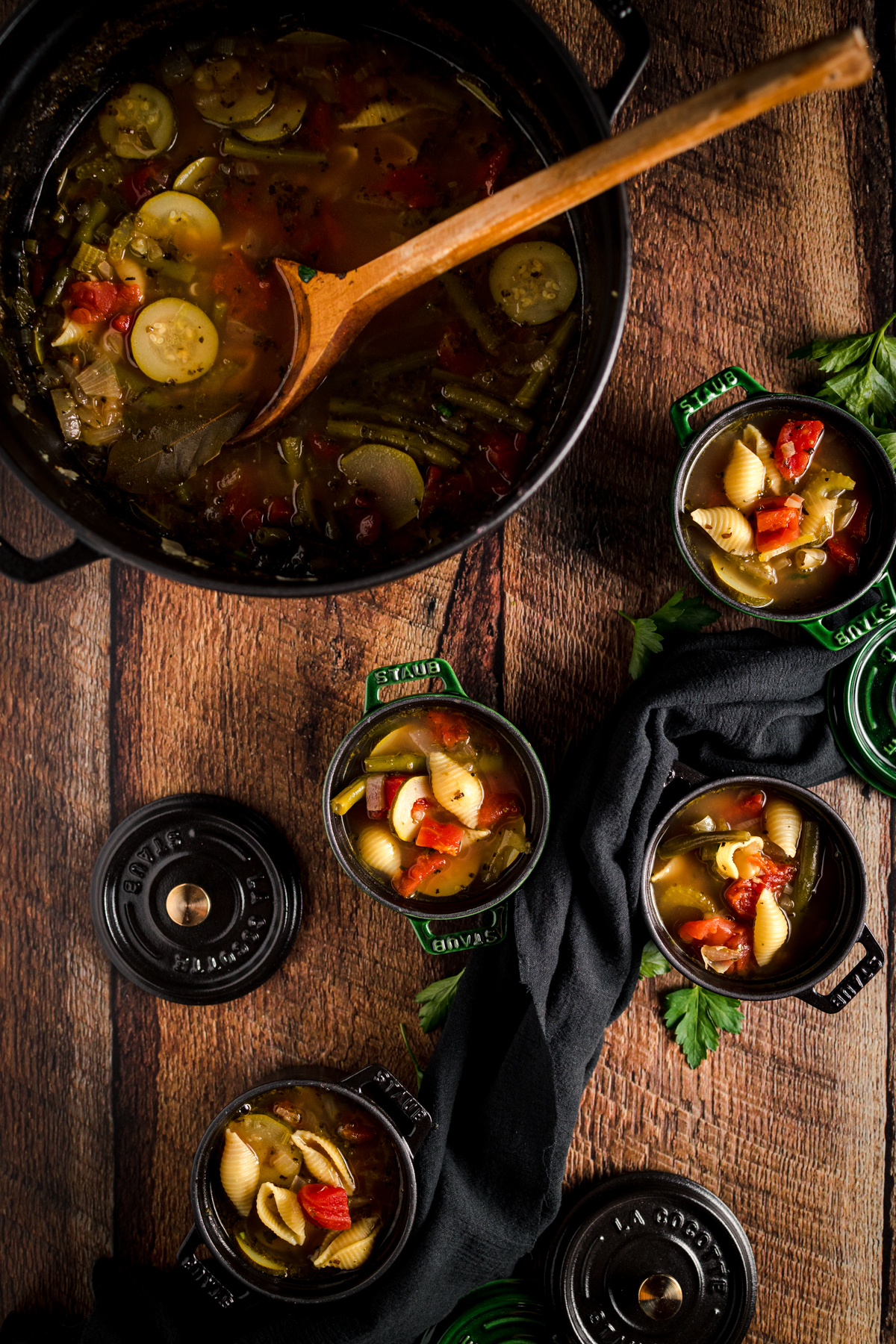 A pot of soup with vegetables and a wooden spoon.